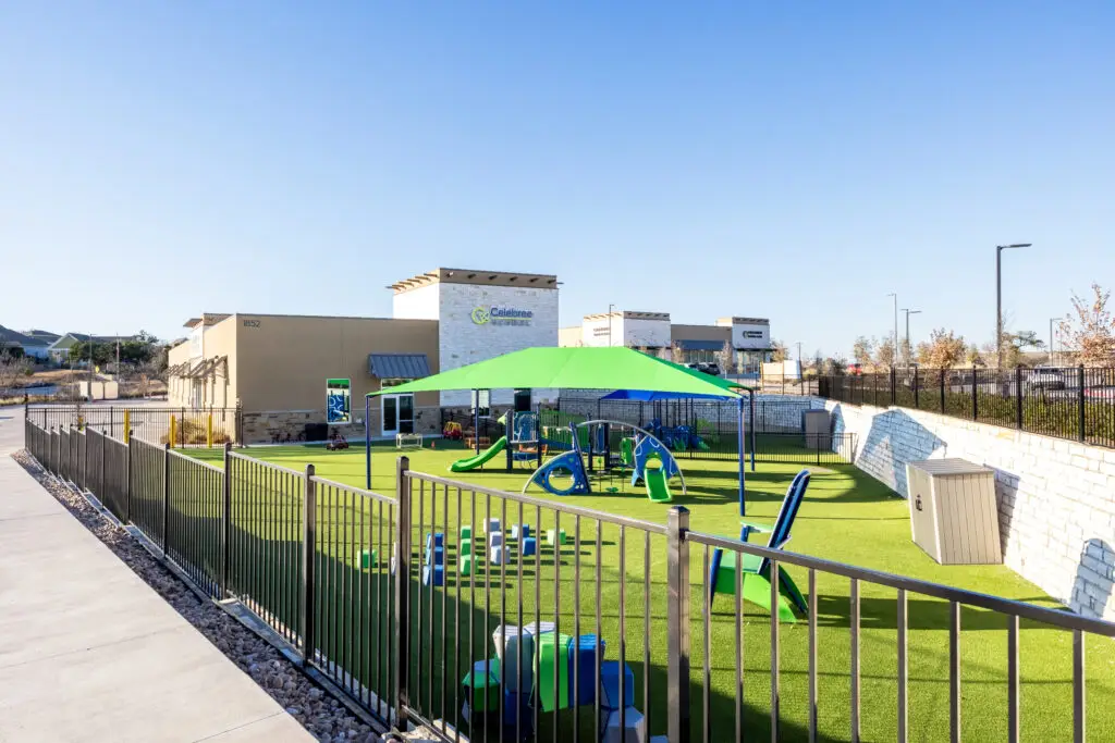 Outdoor playground with turf and shade structures at Celebree School in Leander Texas constructed by Synergy Commercial Construction