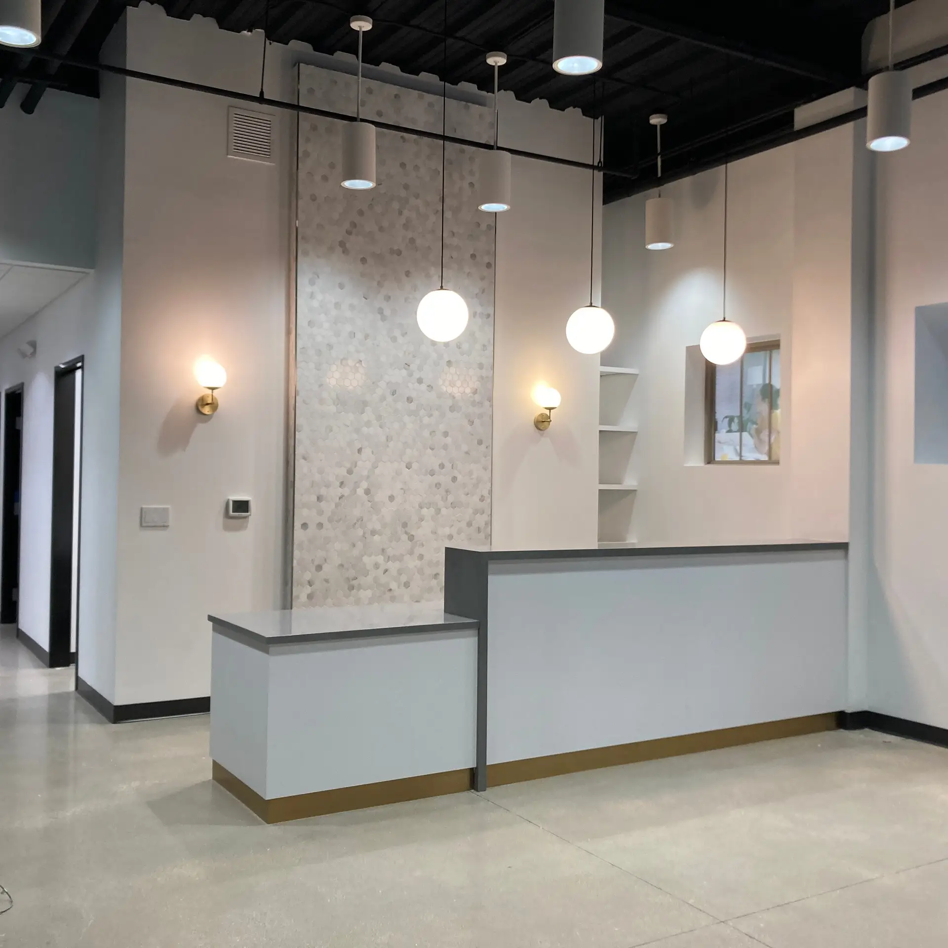 Modern reception desk with pendant lighting and clean finishes at Lumino Vision, built by Synergy Commercial Construction