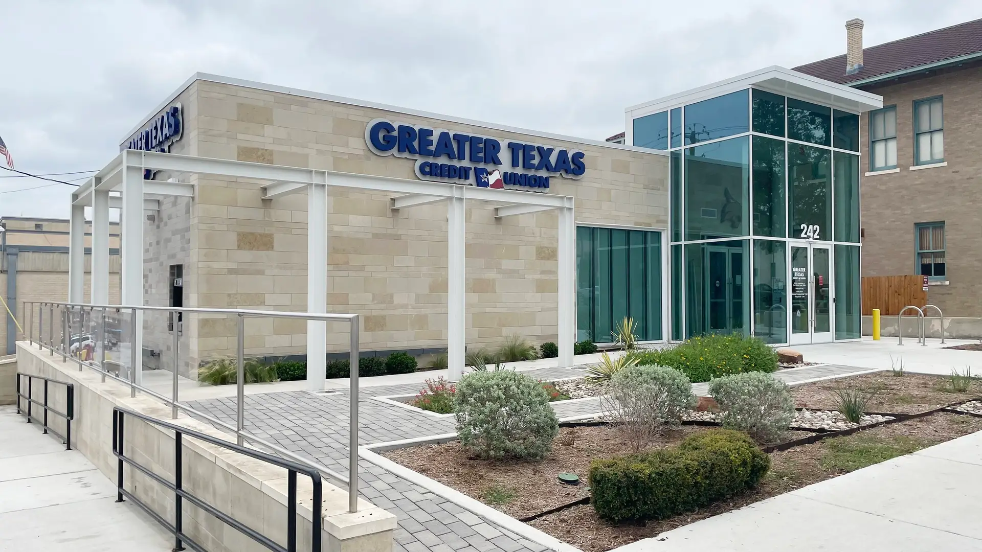 Front exterior of the remodeled Greater Texas Federal Credit Union location featuring updated stone finishes, large windows, and pedestrian access ramps.