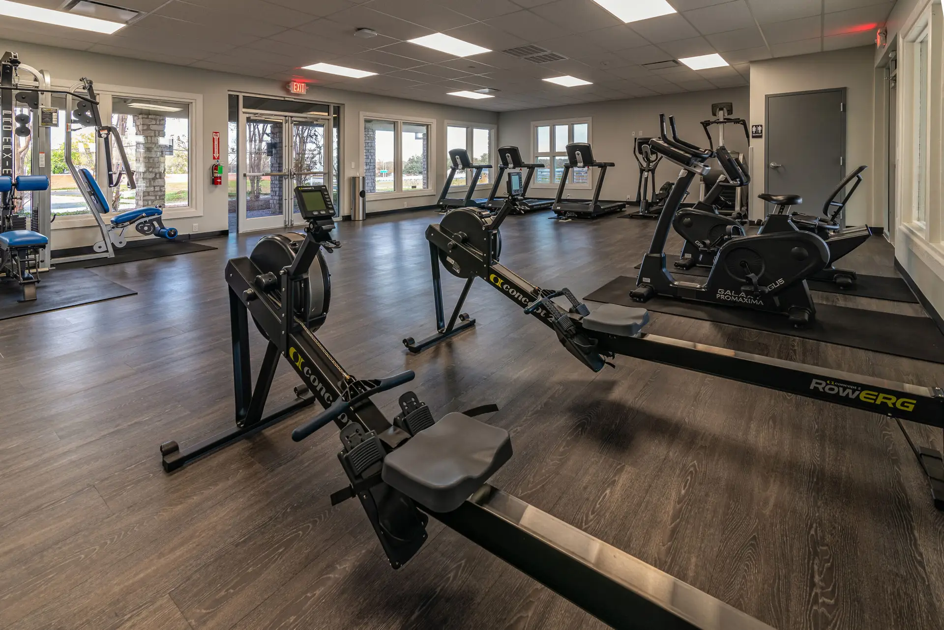 Fitness area at Rockcare Wellness featuring rowing machines, cardio equipment, and dark wood flooring completed during the remodel
