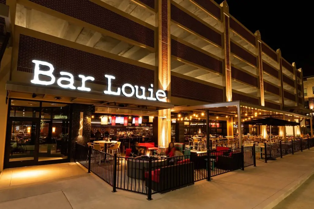 Covered outdoor patio with heaters, lounge seating, and illuminated dining areas completed during the Bar Louie remodel by Synergy Commercial Construction.