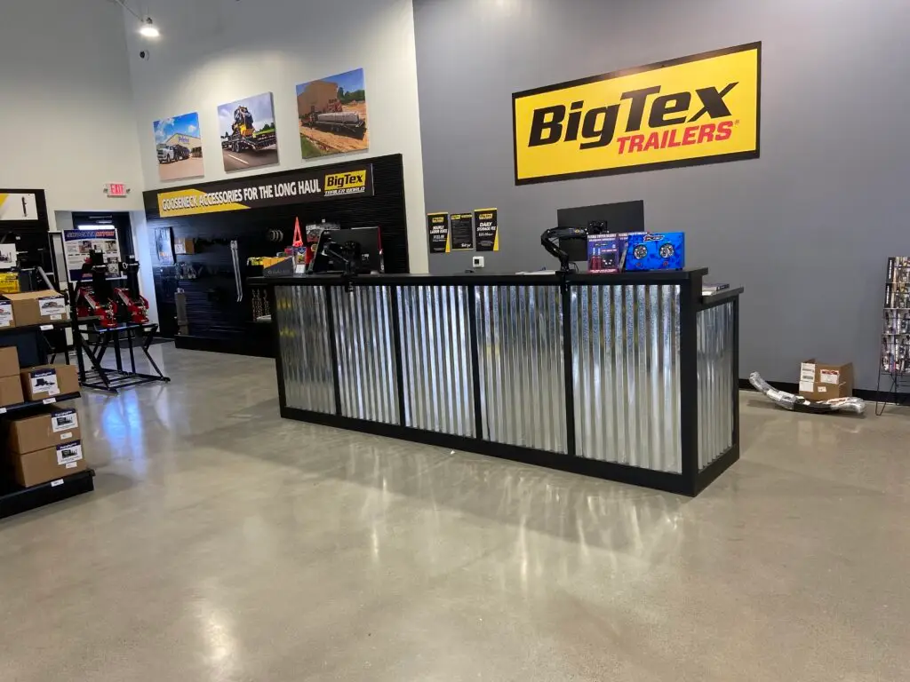 Customer service counter and retail sales area with corrugated metal finishes and branded signage at Big Tex Trailers.