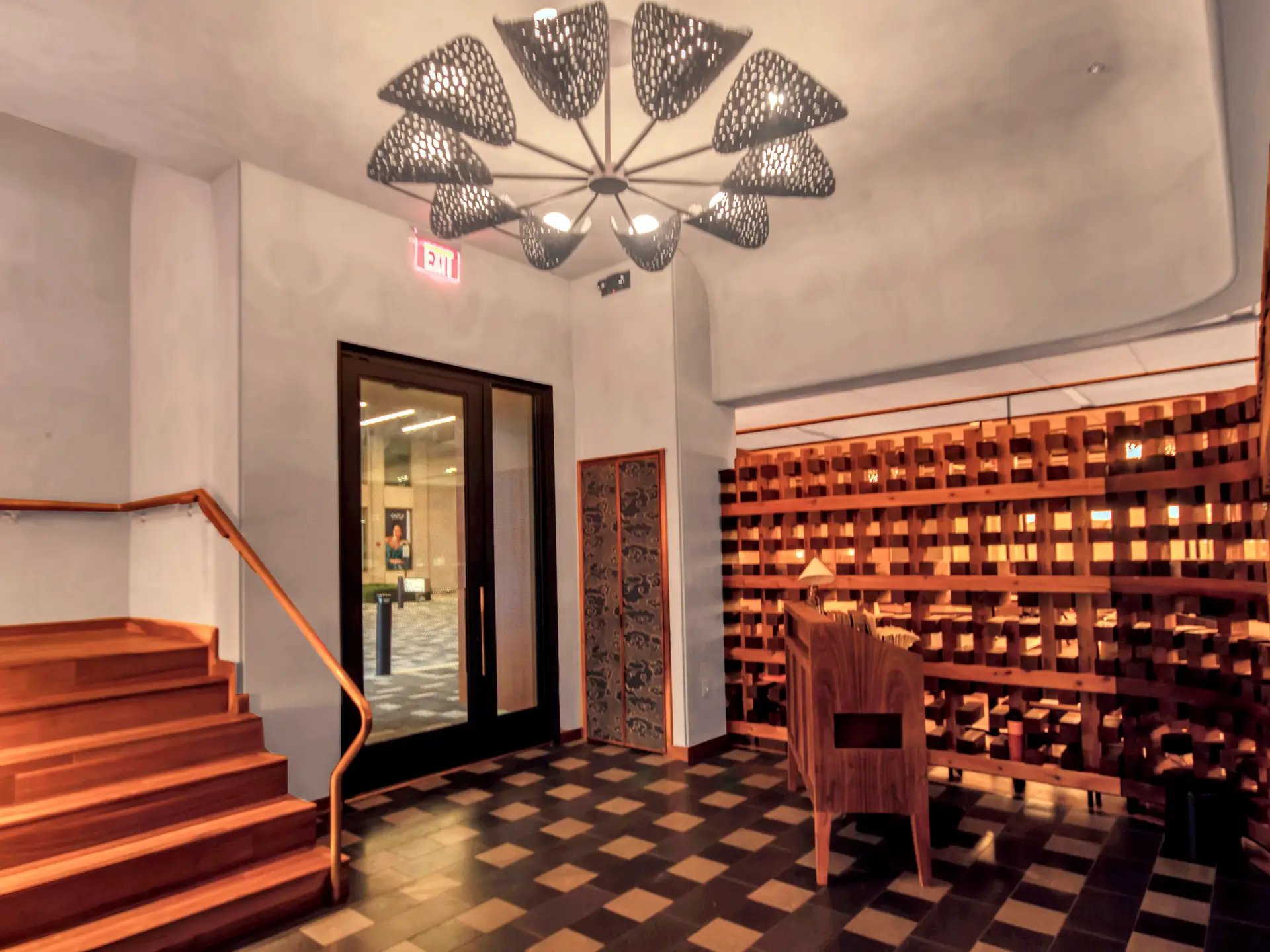 Entry space with custom wood host stand, decorative lighting fixture, wood staircase, and partition wall details.