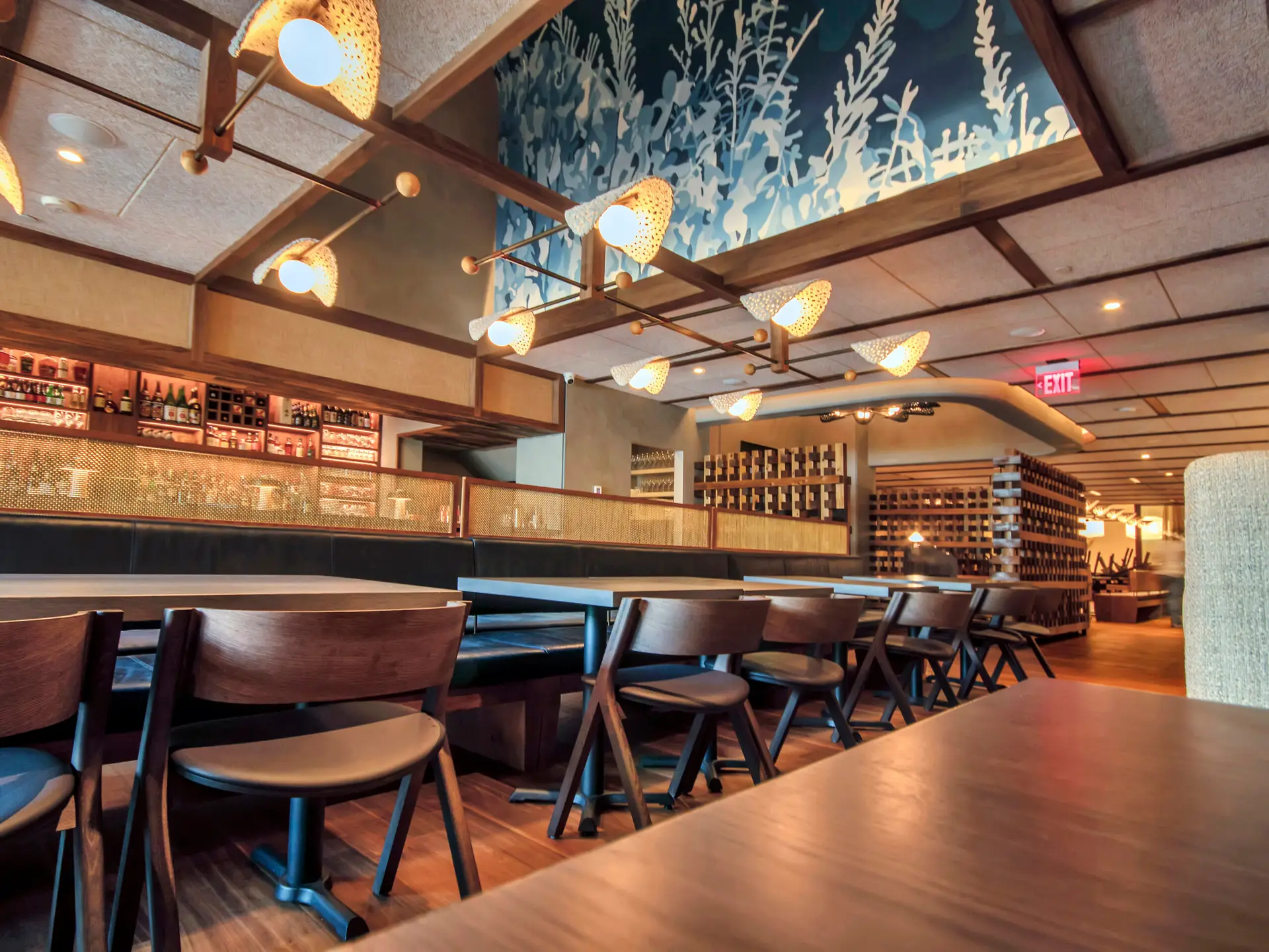 Main dining room with wood accents, custom lighting, upholstered seating, and decorative wall features.
